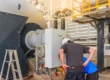 Technicians performing boiler preventative maintenance plans service on industrial boiler control panel and burner system