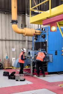 Technicians performing boiler services on an industrial unit
